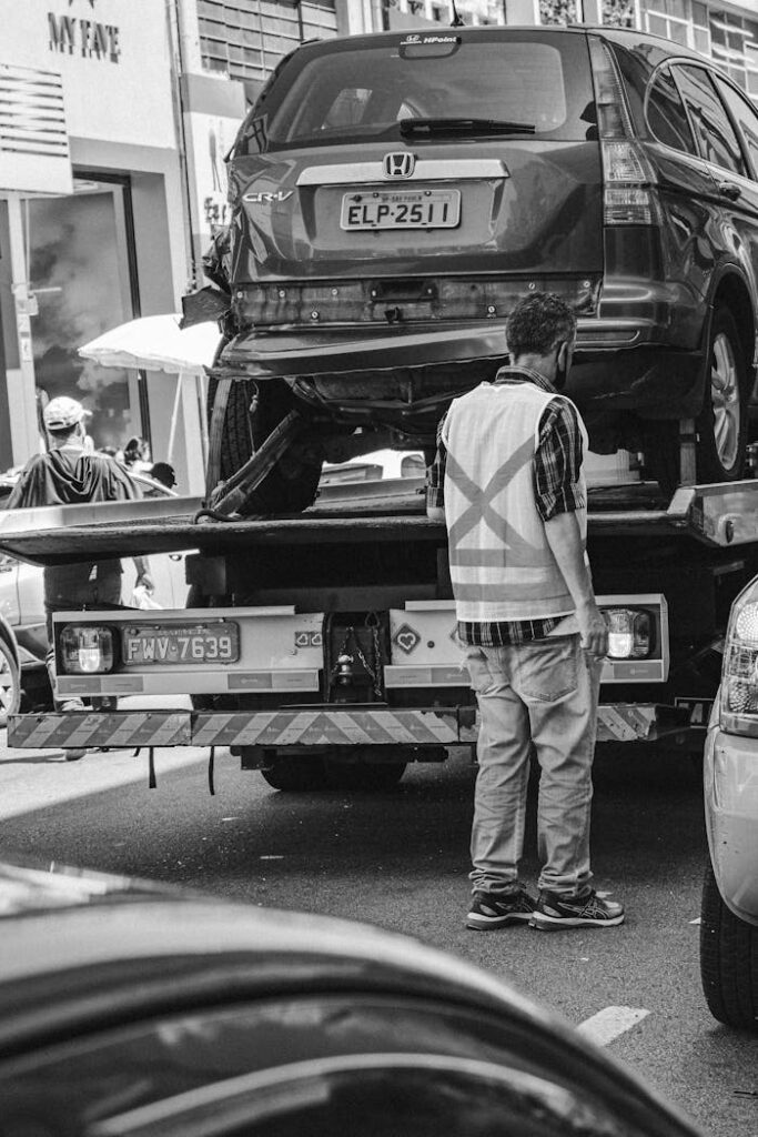 Grayscale image of a tow truck loading a vehicle on a busy street in São Paulo.